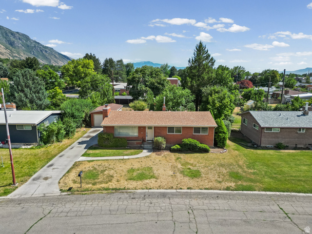 542 East 3400th Street North Provo, UT 84604 - Photo 30 of 39 Red brick residence featuring a brown shingle roof, attached garage, front yard with mature landscaping, and a concrete driveway
