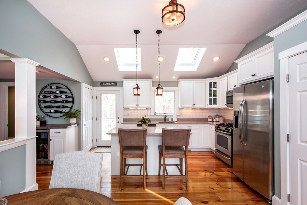 250 First Parish Road Scituate, MA 02066 - Photo 6 of 25 a kitchen with stainless steel appliances kitchen island granite countertop a dining table chairs and a refrigerator