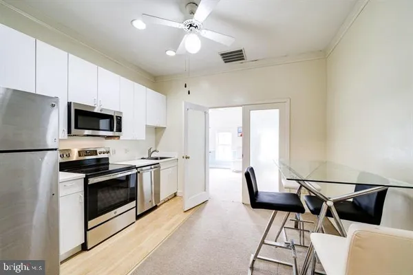 a kitchen with stainless steel appliances granite countertop a stove top oven a sink a dining table and chairs