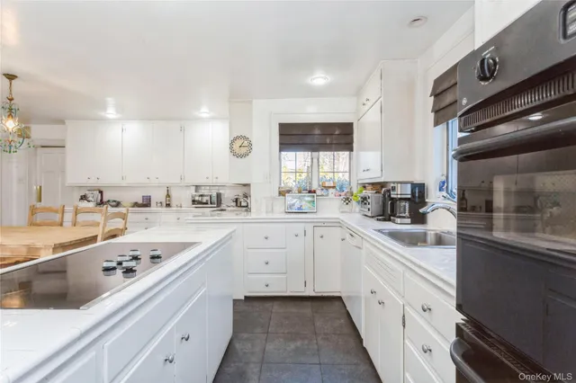 a kitchen with a sink dishwasher a stove and white cabinets with wooden floor