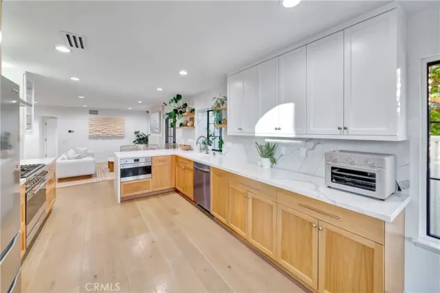 a kitchen with stainless steel appliances granite countertop a refrigerator a stove and a sink