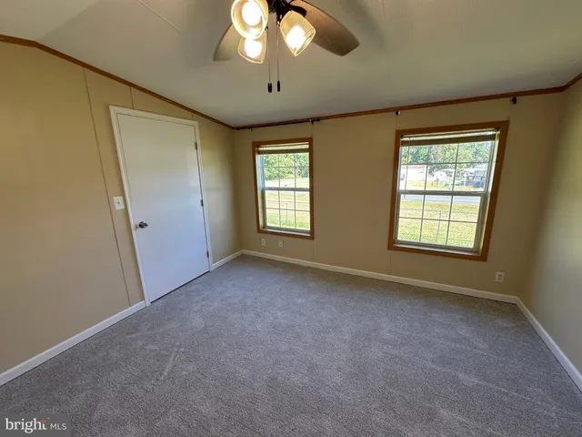 a furnished livingroom with a ceiling fan and windows