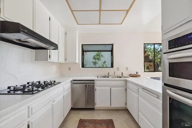 a kitchen with granite countertop a sink a stove and cabinets