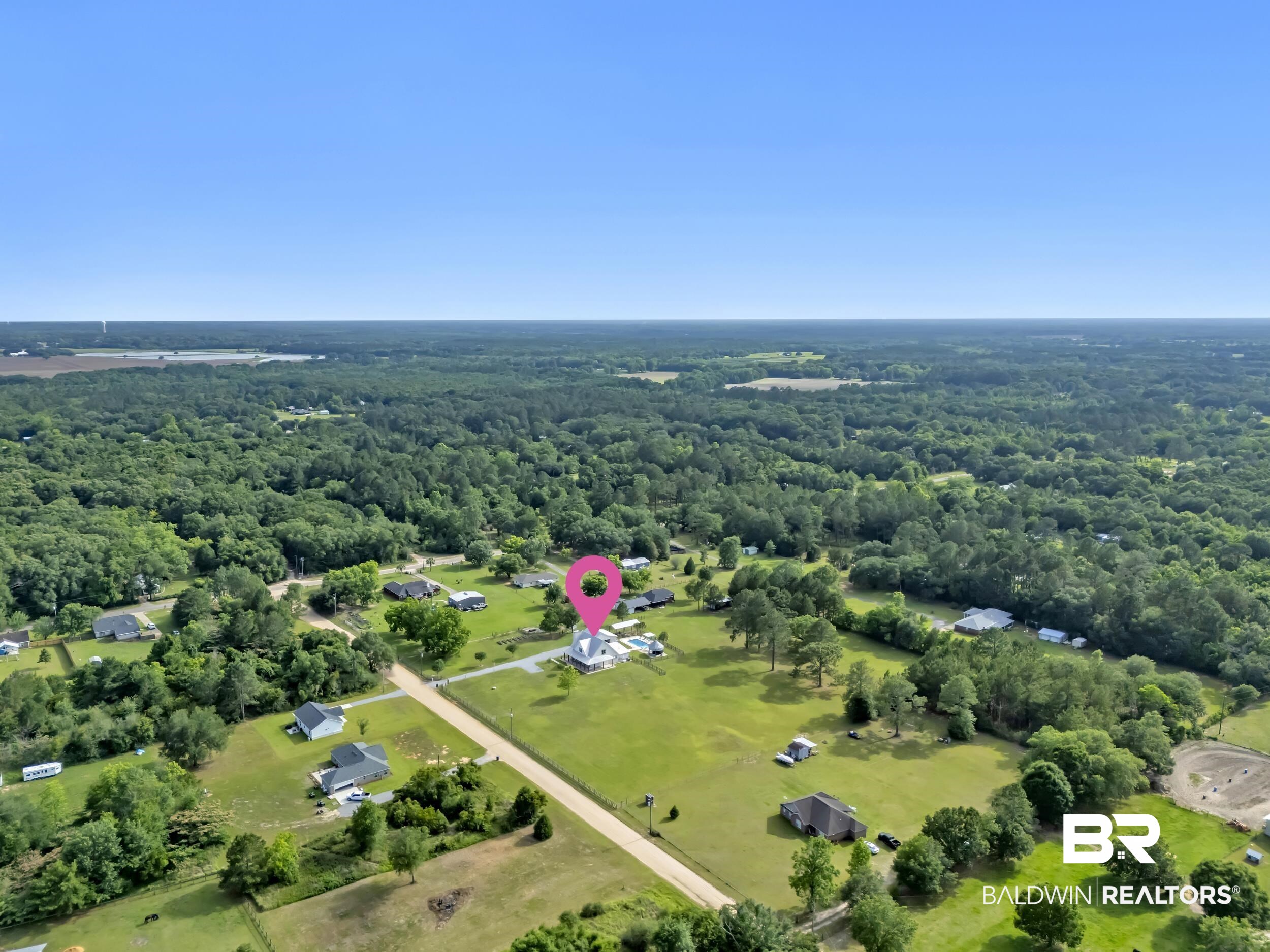 6576 Ranch Loop Road East Grand Bay, AL 36541 - Photo 35 of 39 Expansive rural setting with a residential property featuring a light-colored exterior and a dark roof, surrounded by mature trees and verdant fields