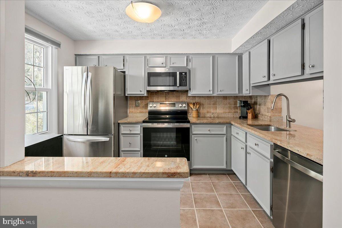 1642 Harvest Green Court Reston, VA 20194 - Photo 9 of 46 a kitchen with granite countertop a refrigerator stove and microwave