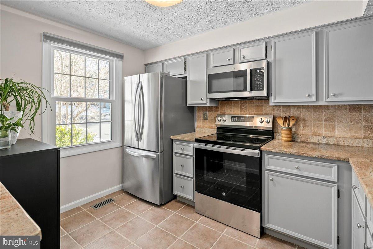 1642 Harvest Green Court Reston, VA 20194 - Photo 10 of 46 a kitchen with stainless steel appliances granite countertop a stove a microwave and a refrigerator