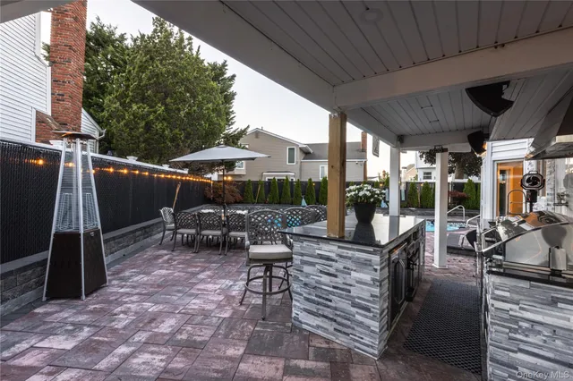 a view of a patio with a table and chairs under an umbrella with a barbeque grill