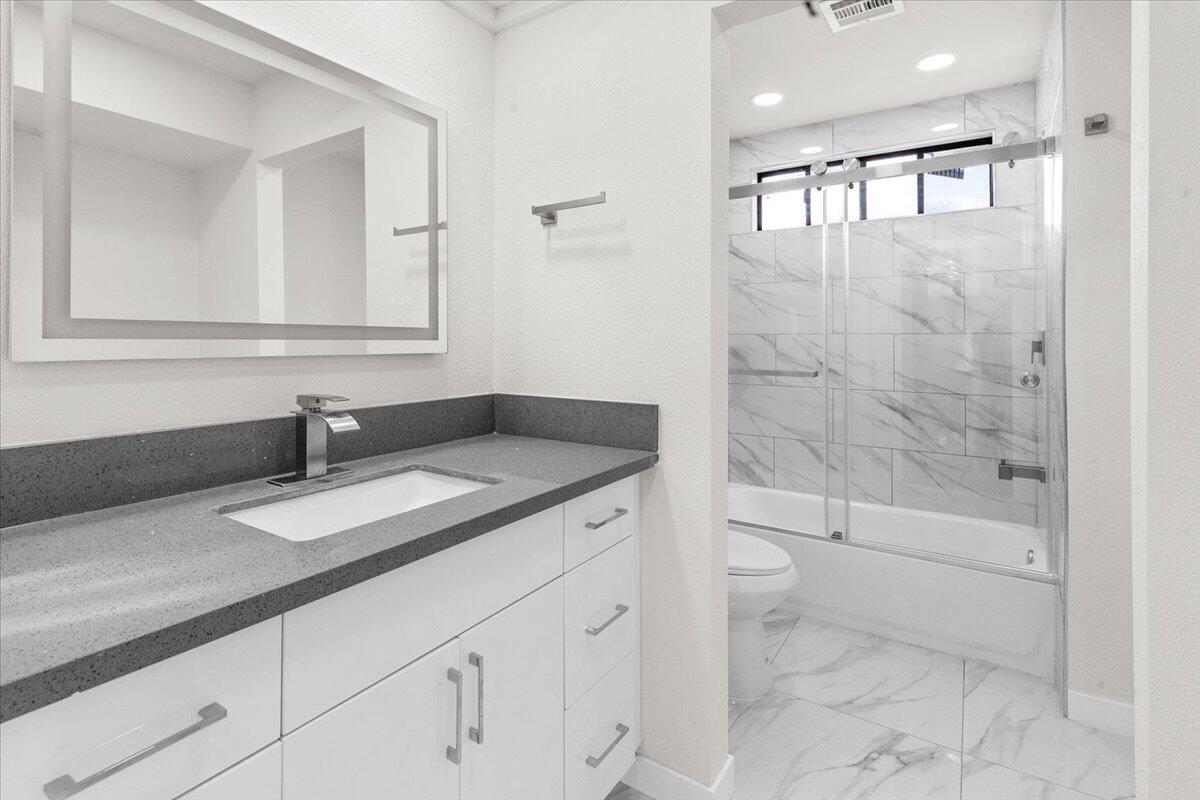 3190 East Vincentia Road Palm Springs, CA 92262 - Photo 25 of 30 a bathroom with a granite countertop sink a toilet a mirror and shower