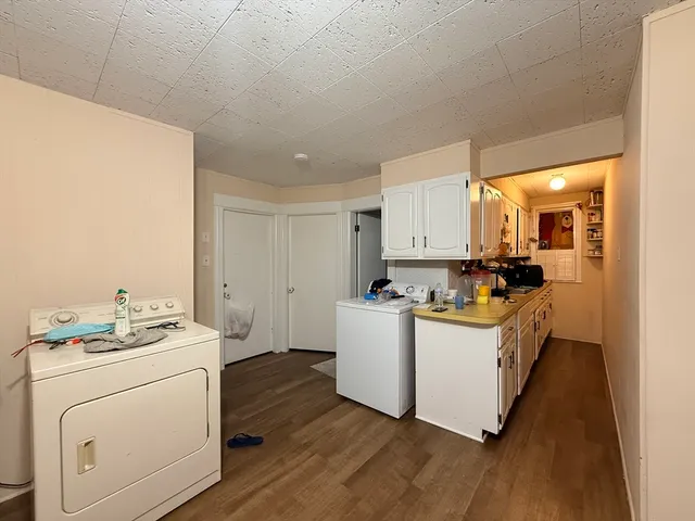 a kitchen with sink a stove and white cabinets with wooden floor