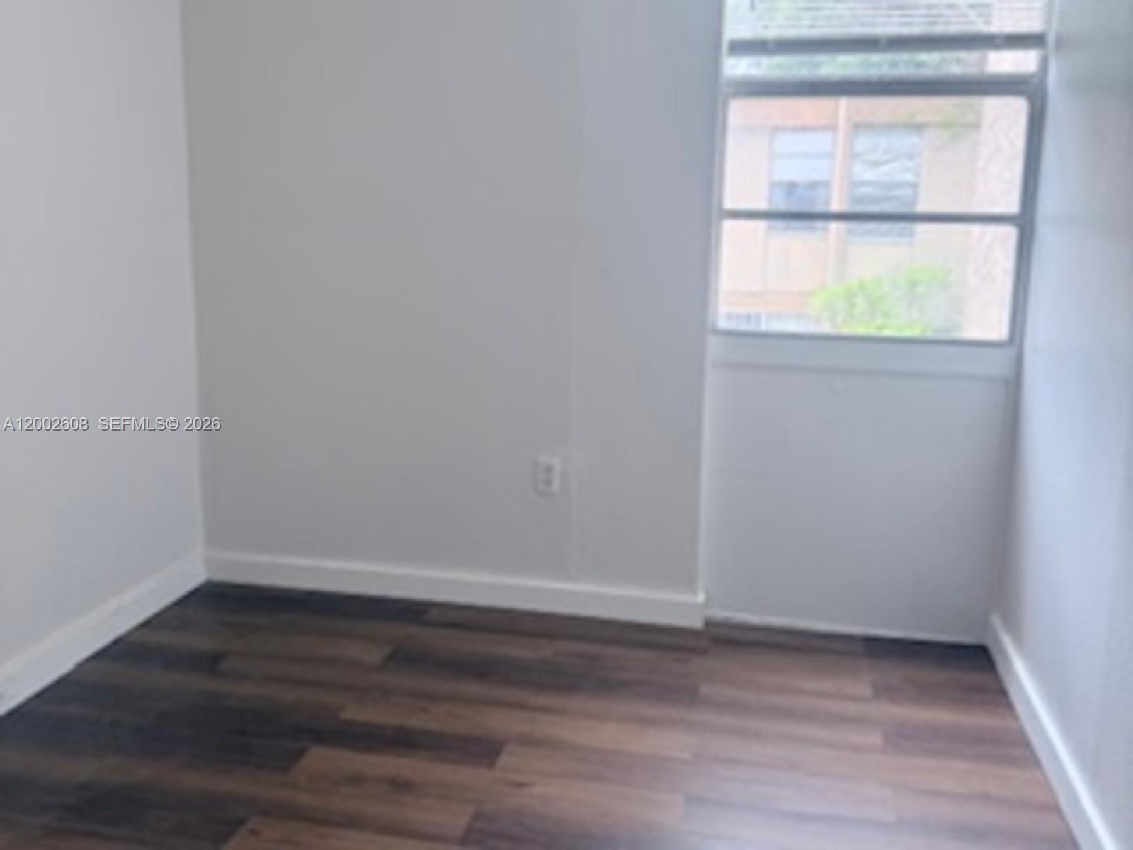 5966 Southwest 68th Street, Unit 109 Miami, FL 33143 - Photo 3 of 12 a view of an empty room with wooden floor and a window