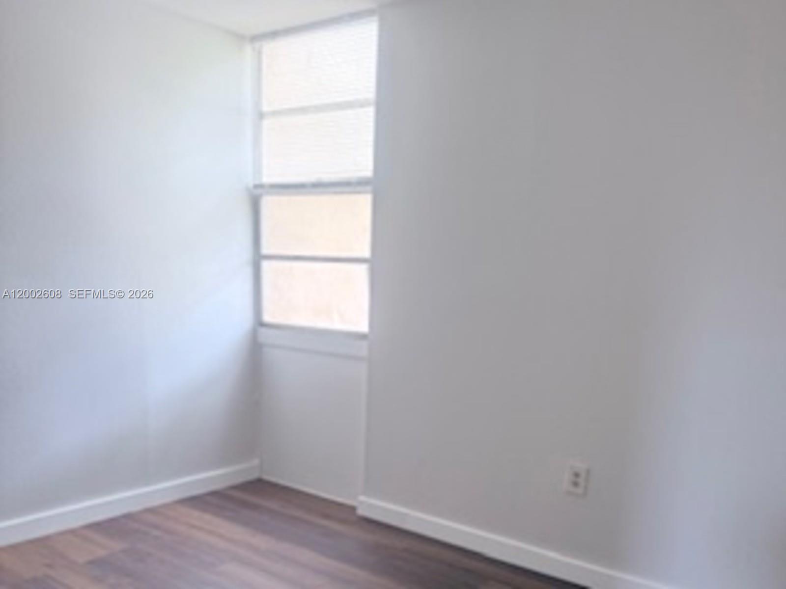 5966 Southwest 68th Street, Unit 109 Miami, FL 33143 - Photo 5 of 12 a view of an empty room with wooden floor and a window