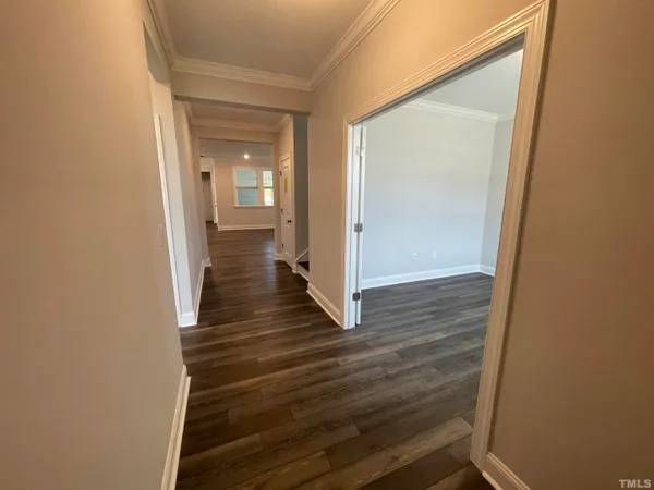 a view of a hallway with wooden floor and a bathroom
