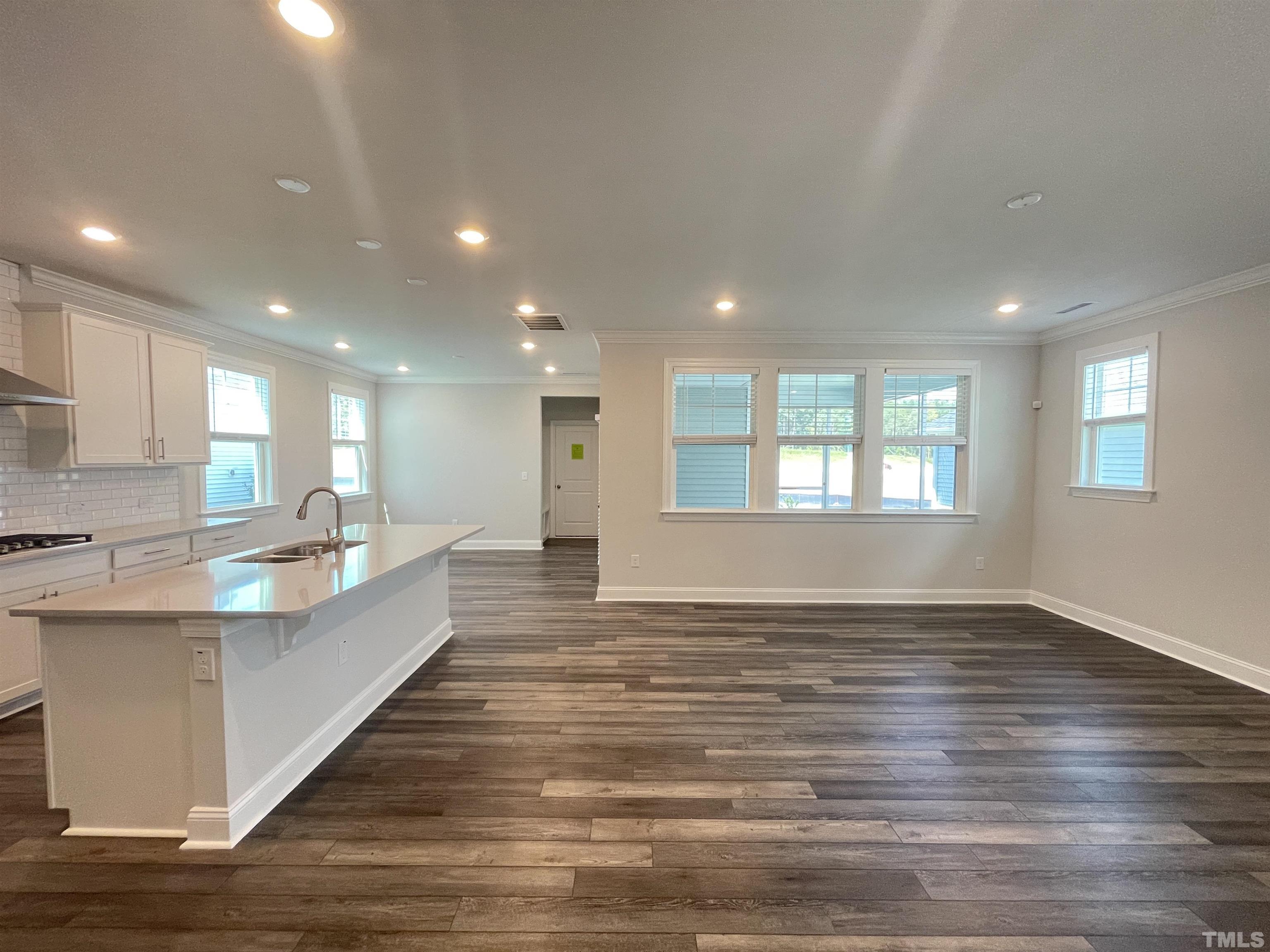 167 Edge Of Auburn Boulevard Clayton, NC 27520 - Photo 6 of 27 a large white kitchen with kitchen island a sink wooden floor and a living room
