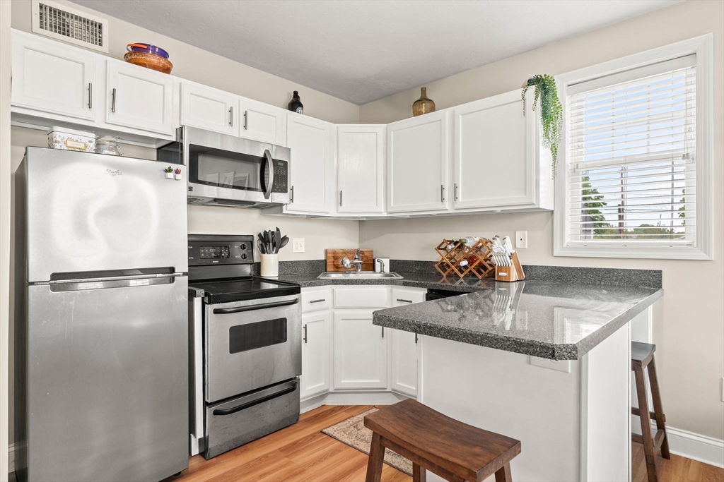 10 Malta Street, Unit 1 Hull, MA 02045 - Photo 7 of 17 a kitchen with stainless steel appliances a stove a sink refrigerator and cabinets