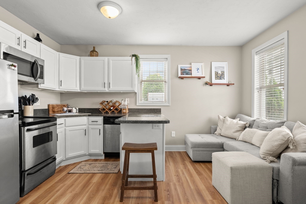 10 Malta Street, Unit 1 Hull, MA 02045 - Photo 10 of 17 a kitchen with stainless steel appliances granite countertop a stove a sink dishwasher and white cabinets with wooden floor