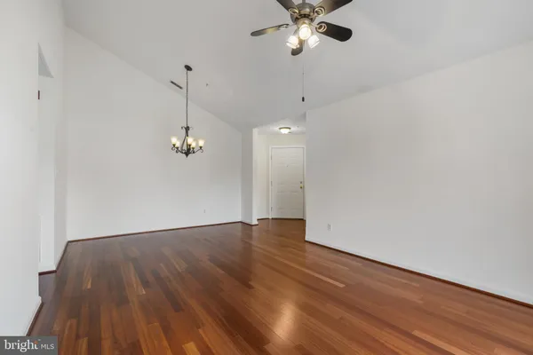 a view of empty room with wooden floor and ceiling fan