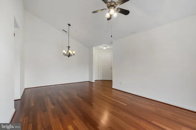 a view of empty room with wooden floor and ceiling fan