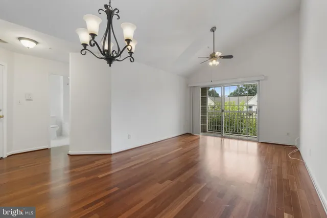 a view of empty room with wooden floor and ceiling fan