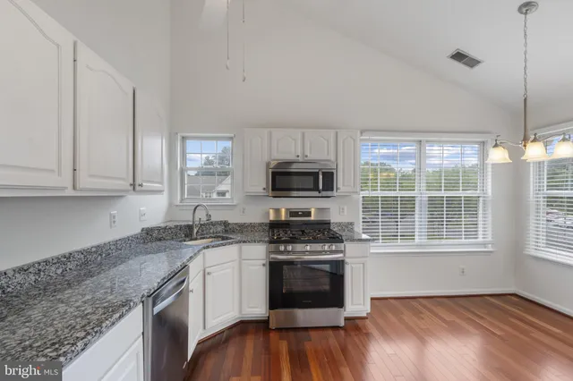 a kitchen with granite countertop stainless steel appliances a stove sink and microwave