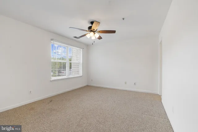 an empty room with a window and a fan