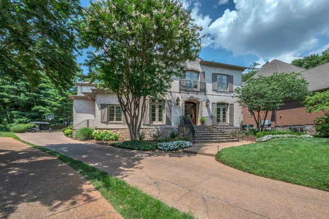 a front view of a house with a yard and a tree
