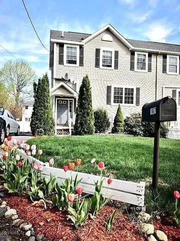 a front view of a house with a yard and potted plants