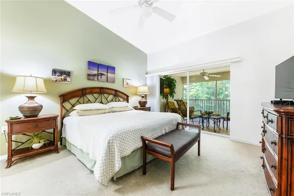 a bedroom with a bed a table and a flat tv screen