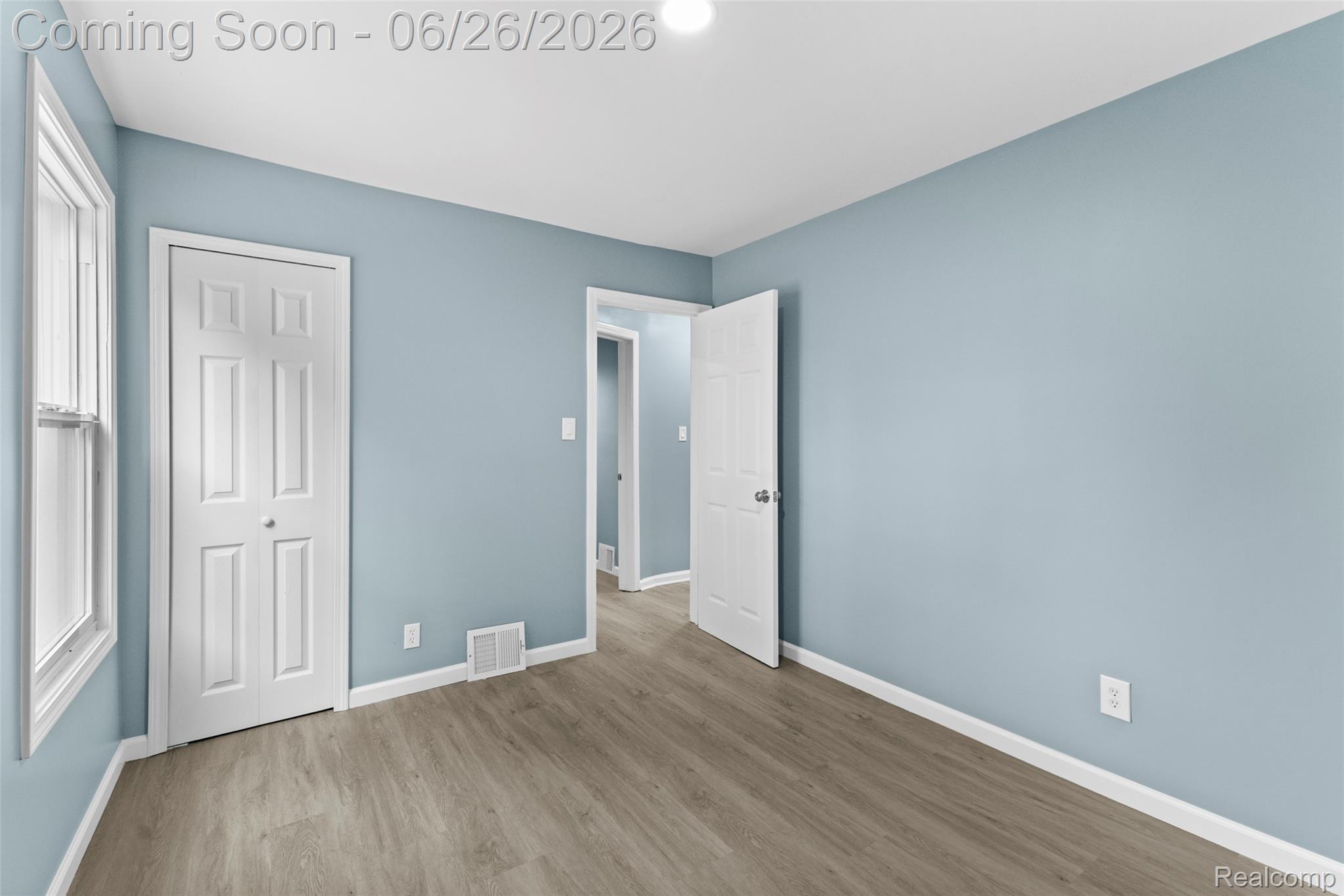 8310 Whitcomb Detroit, MI 48228 - Photo 21 of 26 Interior room featuring light blue walls, wood-finish flooring, white trim, and a window providing natural illumination