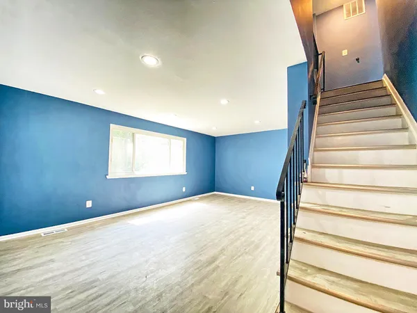 a view of an empty room with stairs and wooden floor