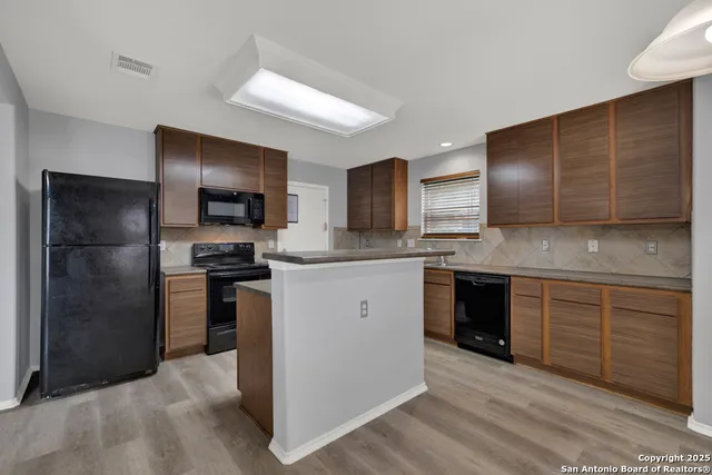 a kitchen with stainless steel appliances kitchen island granite countertop a refrigerator stove and oven