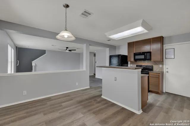 a kitchen with stainless steel appliances granite countertop a refrigerator a stove top oven a sink dishwasher and wooden floor