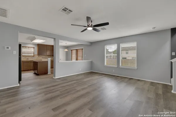 a view of an empty room with a window and wooden floor