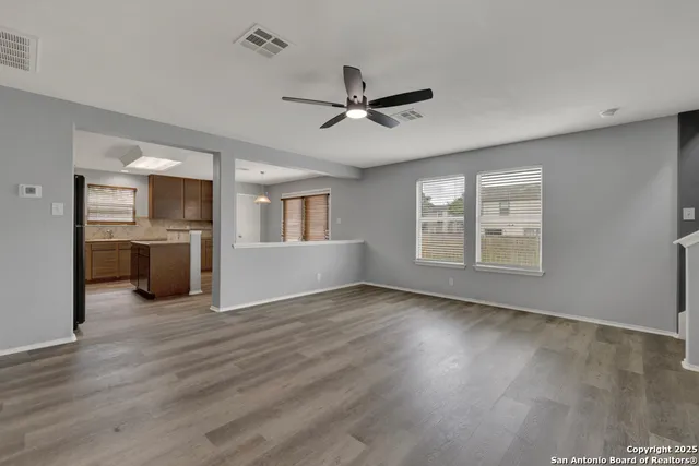 a view of an empty room with a window and wooden floor