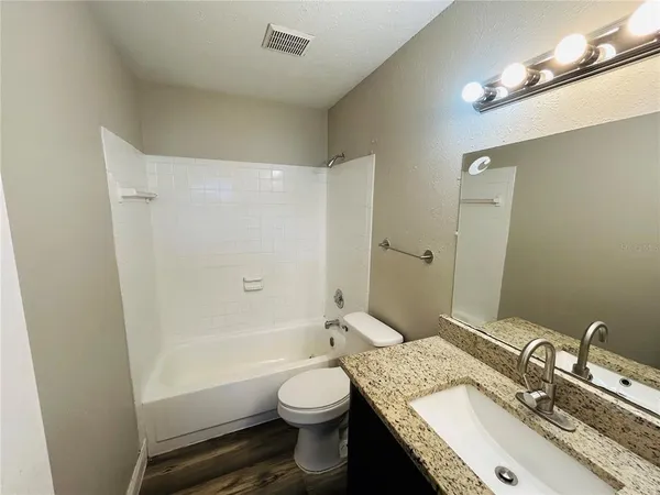a bathroom with a granite countertop sink toilet and shower