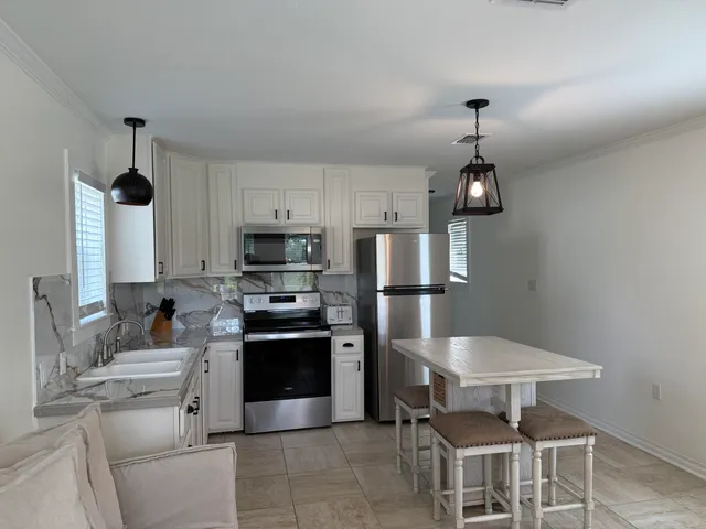 a kitchen with stainless steel appliances kitchen island granite countertop a sink and a refrigerator