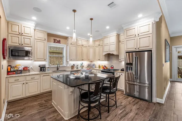 a kitchen with stainless steel appliances granite countertop a kitchen island hardwood floor sink and stove