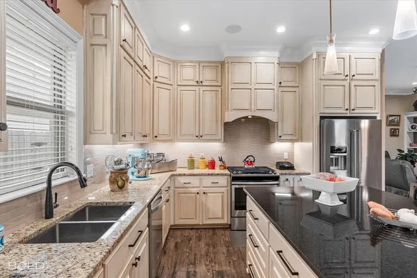 a kitchen with kitchen island granite countertop a sink stainless steel appliances and cabinets