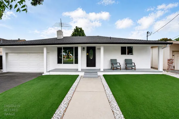 a view of a white house with a big yard and potted plants