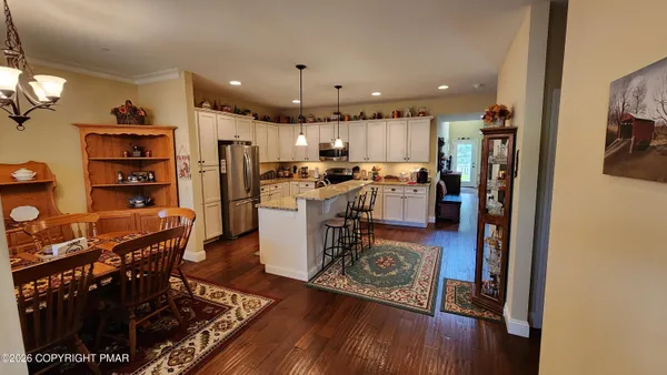 a kitchen with stainless steel appliances granite countertop a refrigerator oven a stove and a dining table with wooden floor