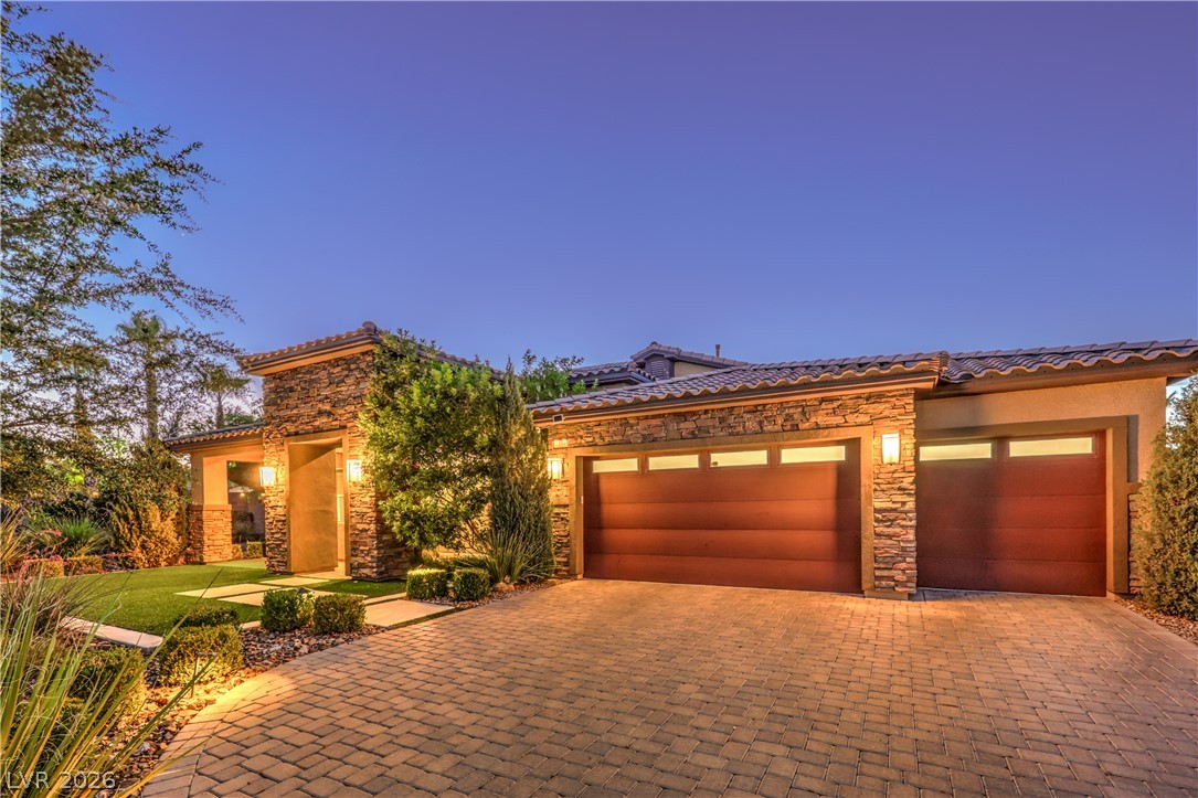 7119 Arabian Ridge Street Las Vegas, NV 89131 - Photo 2 of 73 A striking facade with warm exterior lighting and meticulously paved driveway welcomes you home.