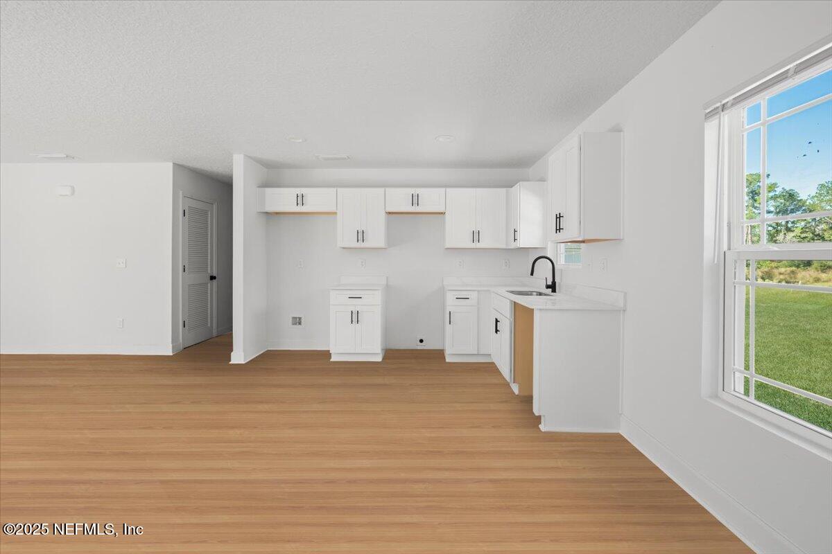 5432 Laredo Street Keystone Heights, FL 32656 - Photo 10 of 23 a view of a kitchen with white cabinets and wooden floor