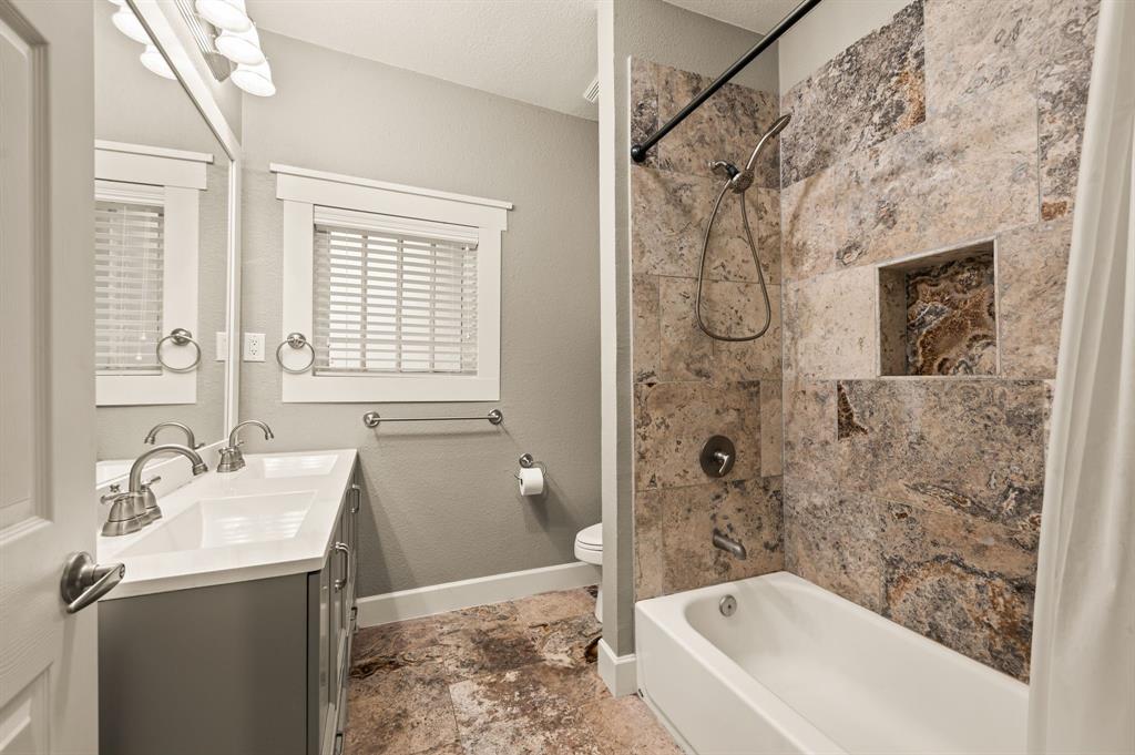 800 North Clements Street Gainesville, TX 76240 - Photo 17 of 27 a bathroom with a granite countertop sink a toilet and shower