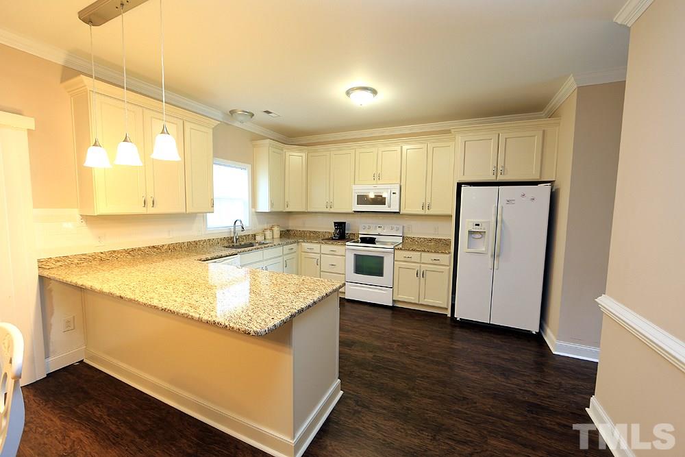 4609 Pearl Road Raleigh, NC 27610 - Photo 3 of 12 a kitchen with stainless steel appliances granite countertop a sink a refrigerator and white cabinets with wooden floor