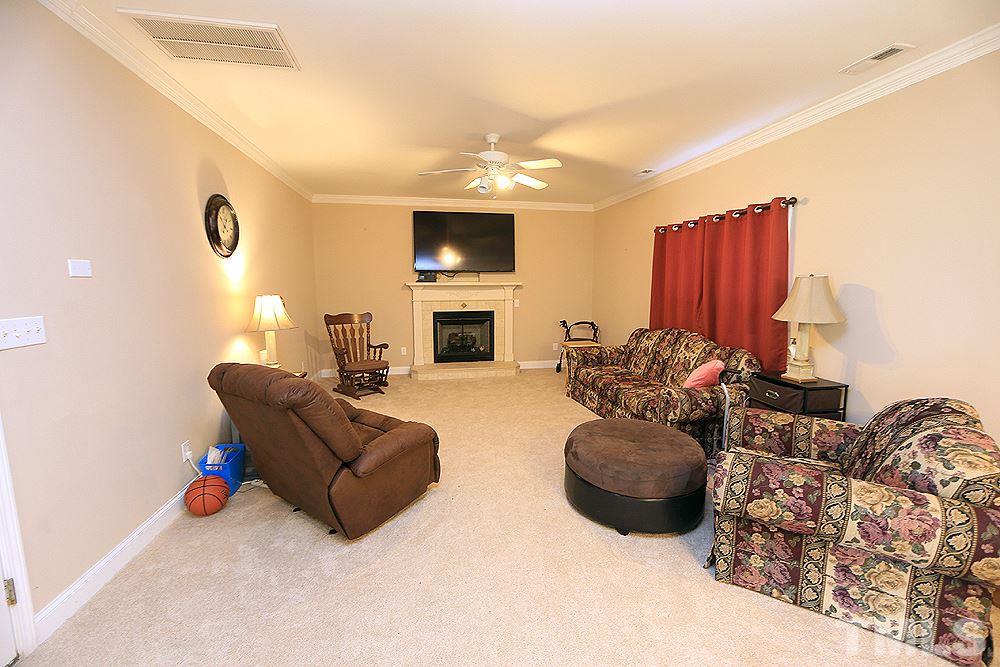 4609 Pearl Road Raleigh, NC 27610 - Photo 5 of 12 a living room with furniture a fireplace and a flat screen tv