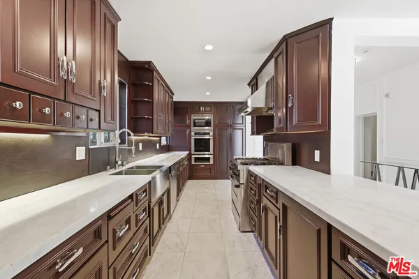 a kitchen with stainless steel appliances granite countertop a sink a stove and a refrigerator