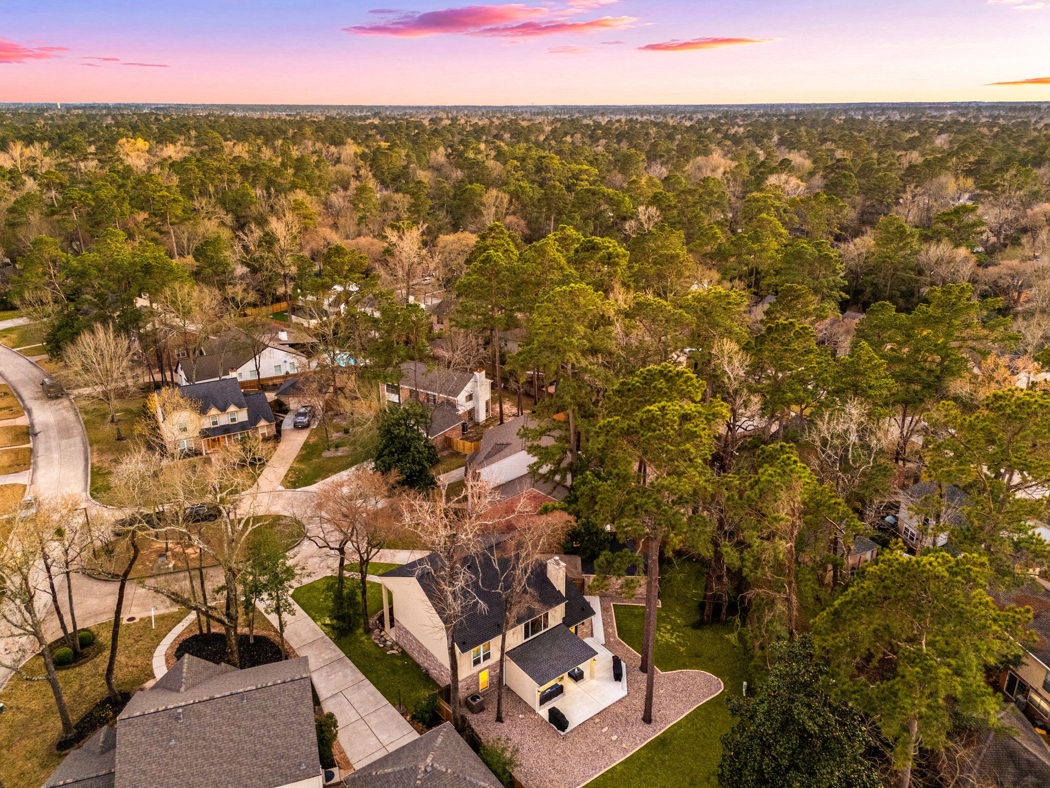 57 Fire Flicker Place Spring, TX 77381 - Photo 11 of 11 This aerial showcases the backside of 57 Fire Flicker. The sunset sky adds a warm glow to the tranquil environment. The backyard faces North.