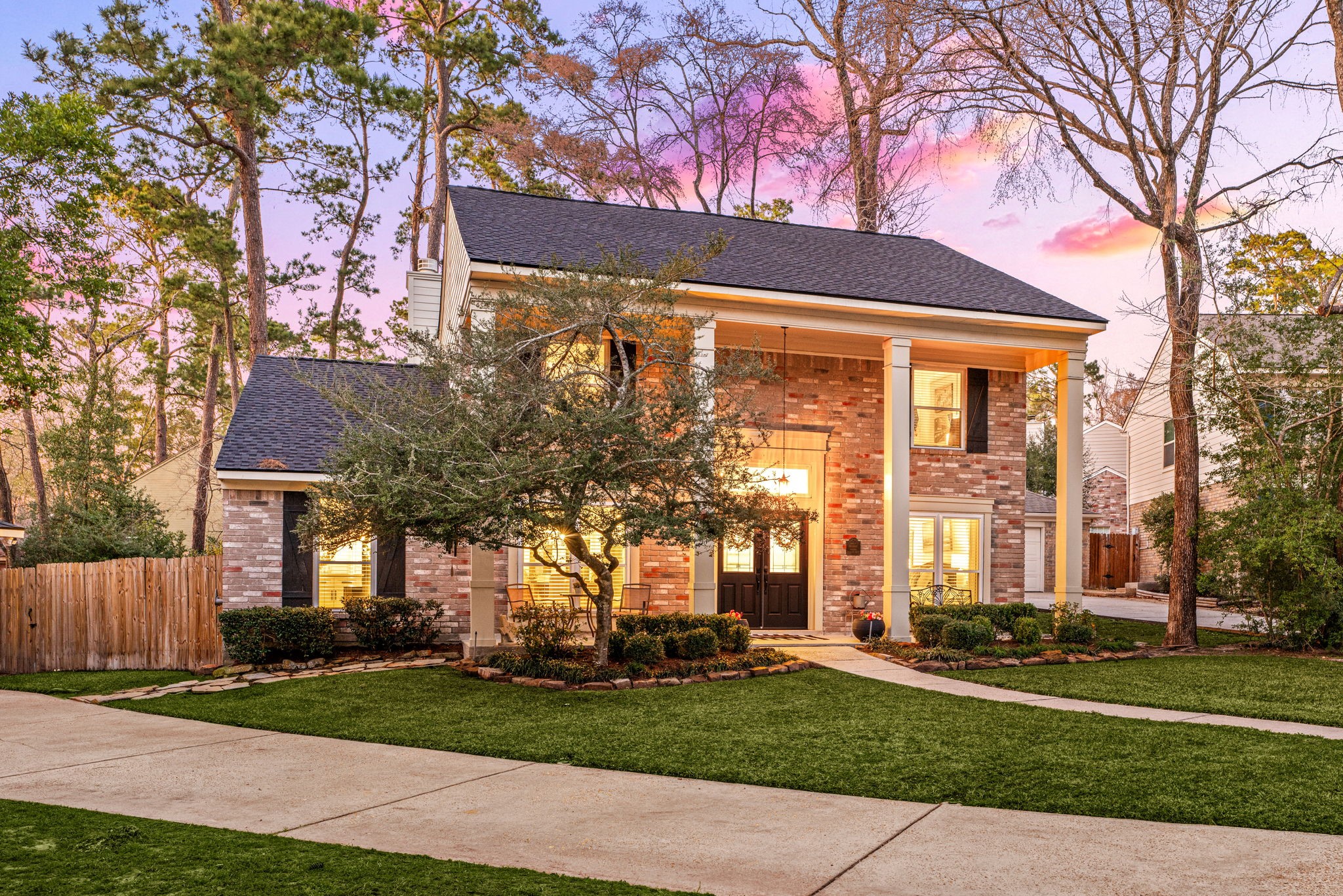 57 Fire Flicker Place Spring, TX 77381 - Photo 2 of 11 Nestled among mature, soaring high trees, it offers a well-maintained flower beds and lawn. The warm exterior lighting enhances its inviting curb appeal.