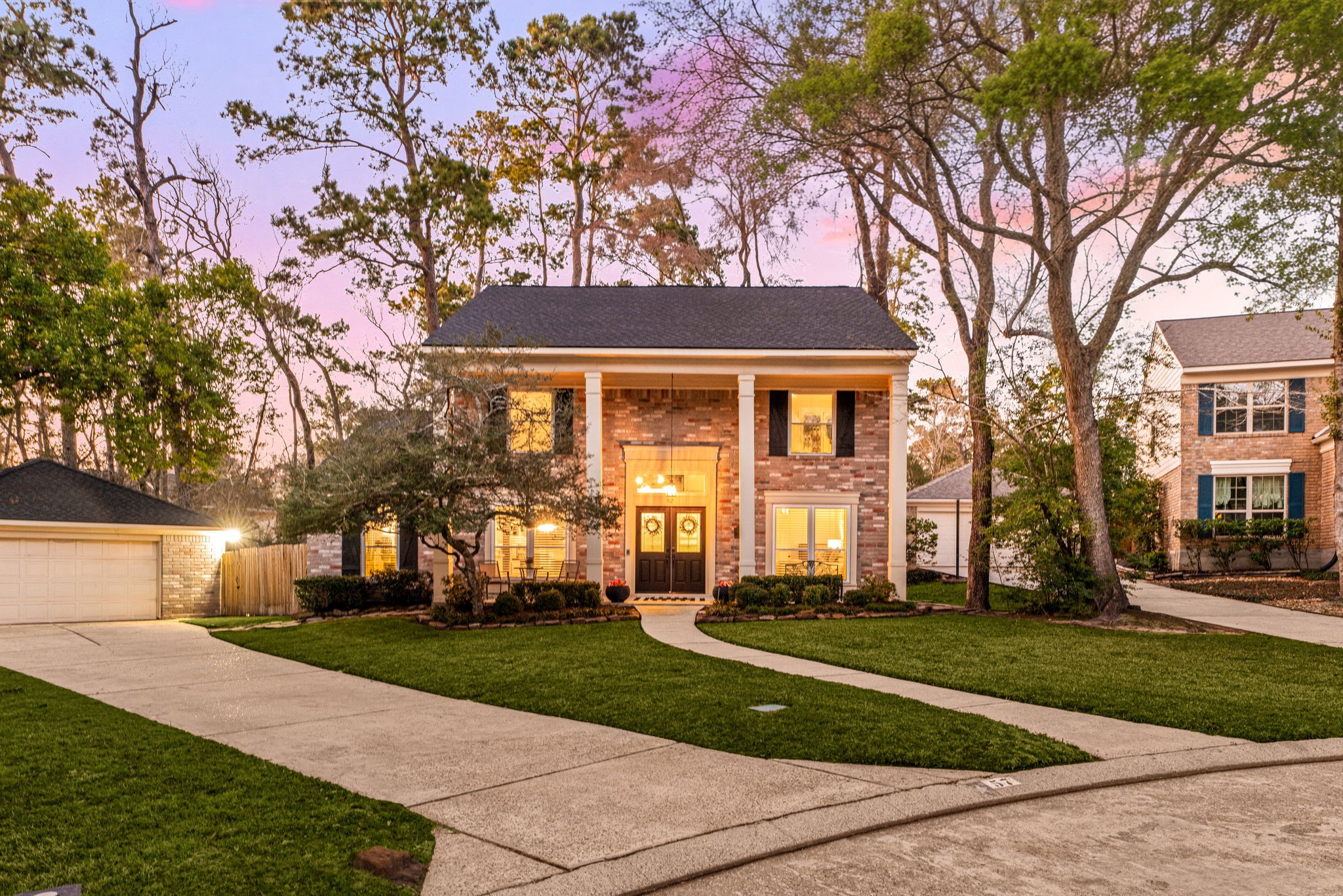 57 Fire Flicker Place Spring, TX 77381 - Photo 3 of 11 This expansive cul-de-sac lot has a spacious front yard and a well-maintained driveway. Nestled among mature trees, it offers a serene atmosphere with warm exterior lighting, perfect for evening relaxation.