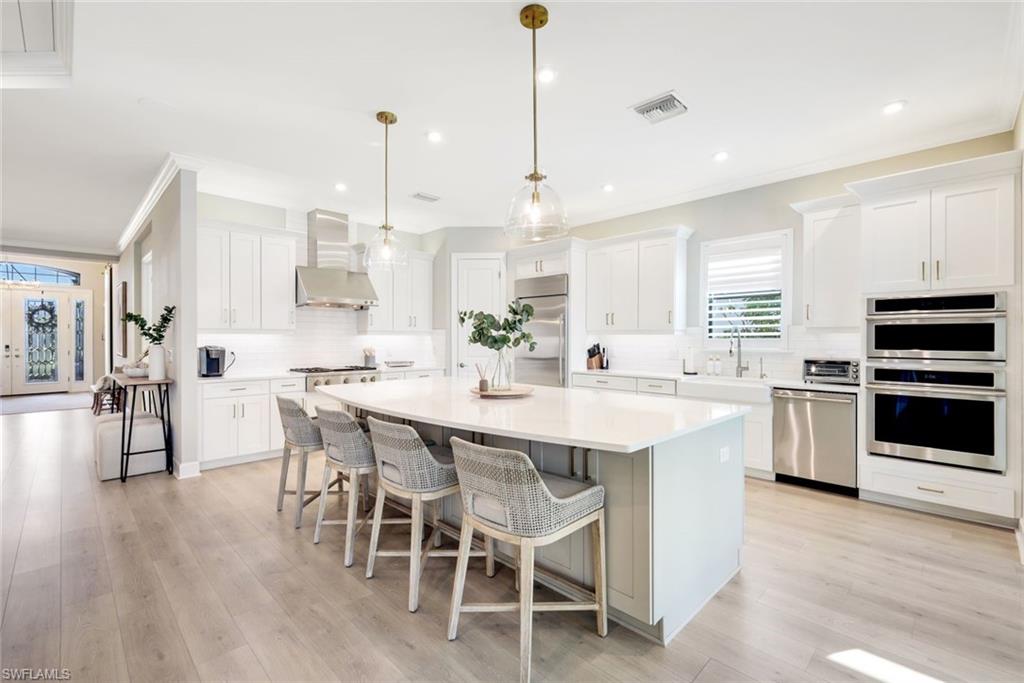 11200 Canal Grande Drive Fort Myers, FL 33913 - Photo 6 of 29 a kitchen with stainless steel appliances kitchen island granite countertop a wooden floor and white cabinets