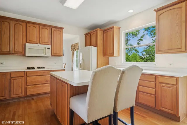 a kitchen with stainless steel appliances granite countertop a refrigerator a sink dishwasher and wooden cabinets with wooden floor